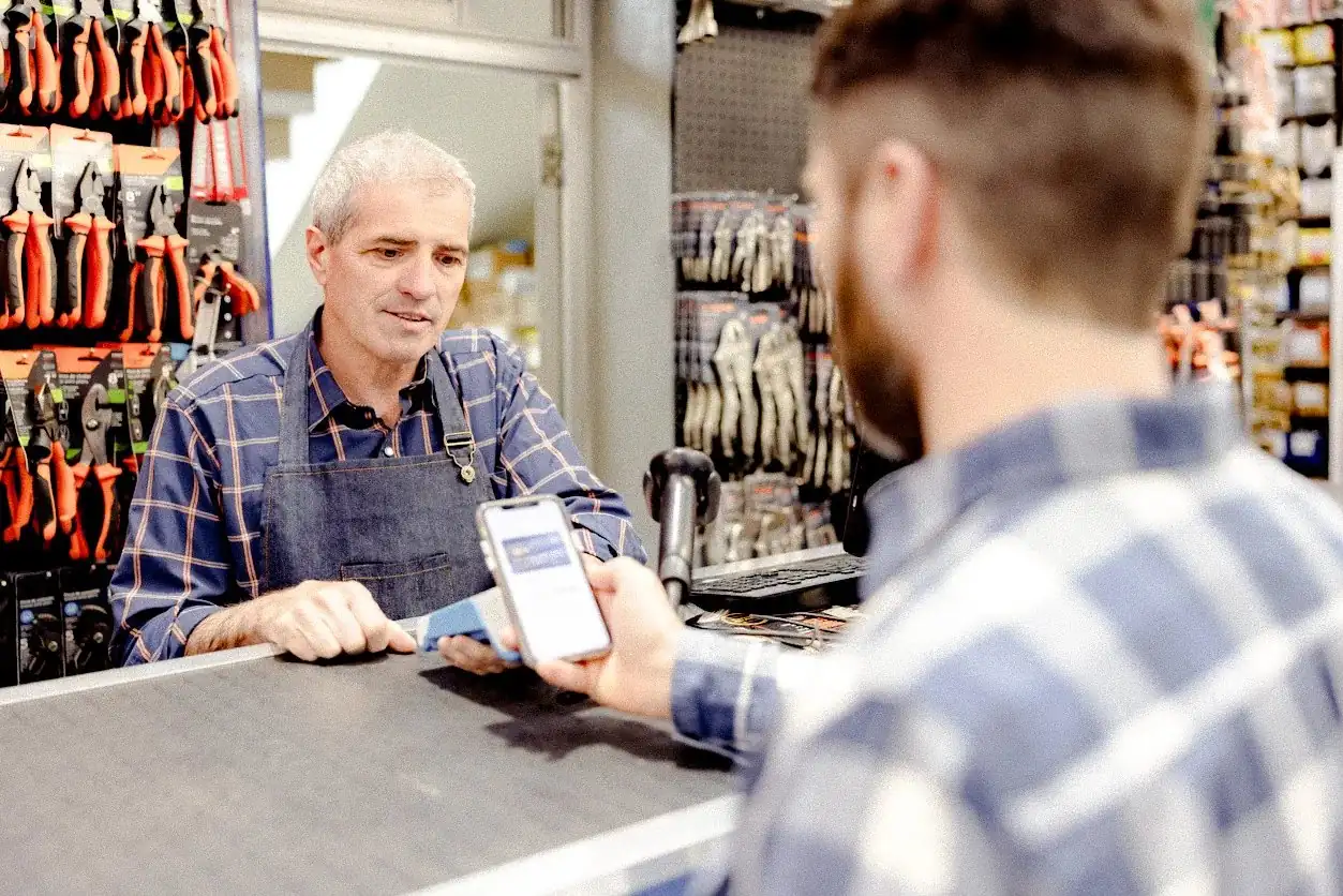 Customer paying with a smartphone contactless wallet at a hardware store checkout counter